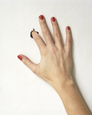 Eine Hand stückt ihren Zeigefinger in ein Loch in einem Papier Eine Hand stückt ihren Zeigefinger in ein Loch in einem Papier