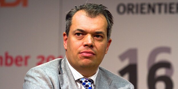 Ein Mann mit schütterem grauem Haar und grauem Anzug guckt melancholisch Ein Mann mit schütterem grauem Haar und grauem Anzug guckt melancholisch