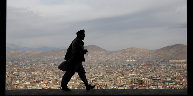 Ein Mann läuft auf einer Mauer mit Bilck auf Kabul Ein Mann läuft auf einer Mauer mit Bilck auf Kabul