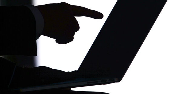 Schattenriss einer Hand, die auf einen Computerbildschirm zeigt Schattenriss einer Hand, die auf einen Computerbildschirm zeigt