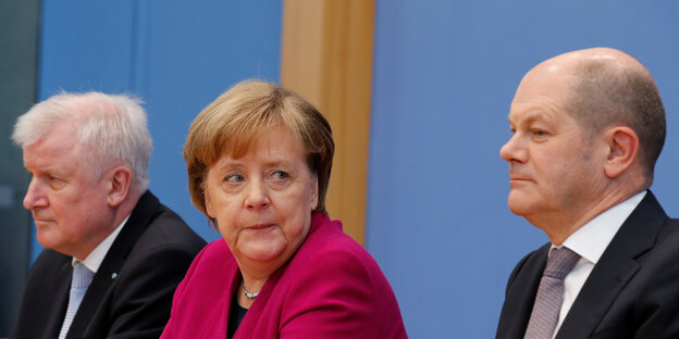 Seehofer, Merkel und Scholz sitzen nebeneinander, Merkel schaut Scholz an Seehofer, Merkel und Scholz sitzen nebeneinander, Merkel schaut Scholz an