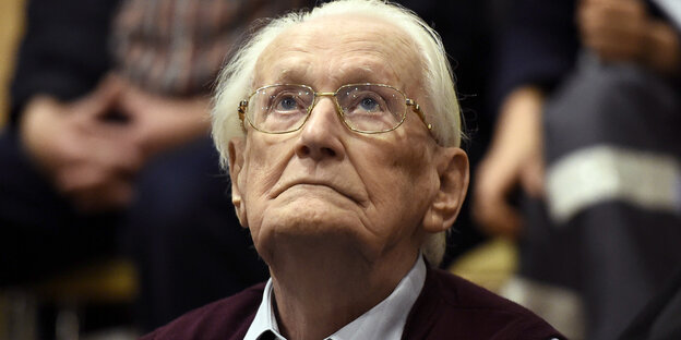 Ein alter Mann mit weißem Haar und Brille schaut nach oben Ein alter Mann mit weißem Haar und Brille schaut nach oben