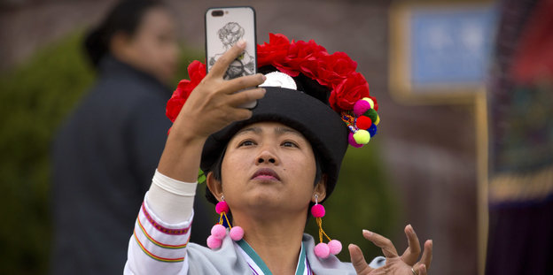 Eine Frau in folkloristischer Kleidung macht ein Selfie.