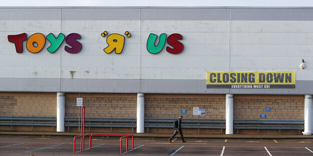 Ein Mann läuft vor der Fassade eines Spielwarenmarktes entlang Ein Mann läuft vor der Fassade eines Spielwarenmarktes entlang