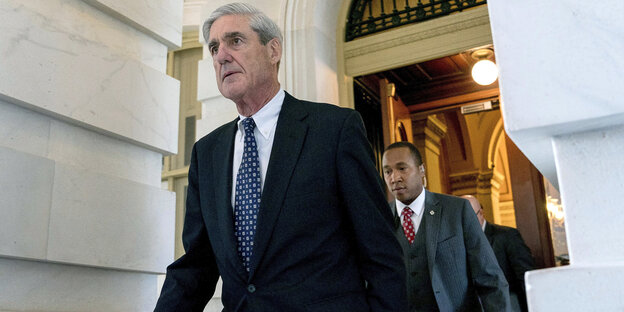 Robert Mueller im Gehen, ein Mann läuft hinter ihm Robert Mueller im Gehen, ein Mann läuft hinter ihm