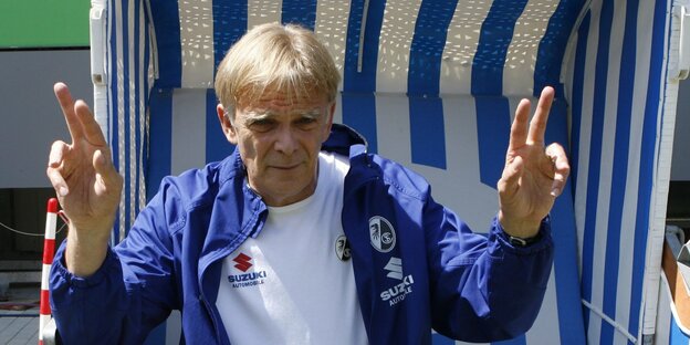 Volker Finke sitzt in einem Strandkorb und formt mit beiden Händen das Victory-Zeichen Volker Finke sitzt in einem Strandkorb und formt mit beiden Händen das Victory-Zeichen