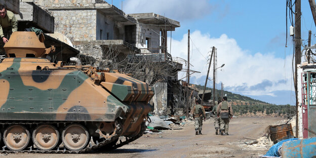 drei Soldaten laufen durch einen total zerstörten Straßenzug, im Vordergrung ein Panzer drei Soldaten laufen durch einen total zerstörten Straßenzug, im Vordergrung ein Panzer