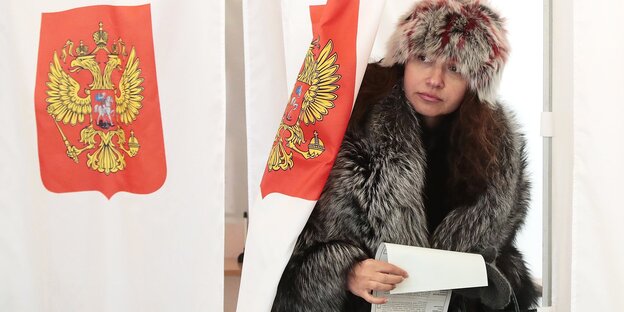 Eine Frau kommt aus einer Wahlkabine Eine Frau kommt aus einer Wahlkabine
