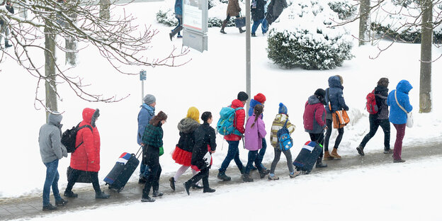 Menschen laufen auf einem Weg durch den Schnee Menschen laufen auf einem Weg durch den Schnee