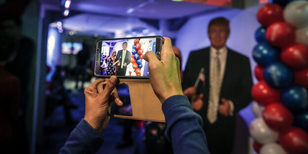 Mit einem Smartphone wird ein Foto von einem Trump-Plakat gemacht Mit einem Smartphone wird ein Foto von einem Trump-Plakat gemacht