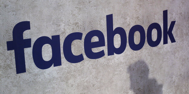 Der Schriftzug "facebook" an einer Wand, darunter der Schatten eines Mannes Der Schriftzug "facebook" an einer Wand, darunter der Schatten eines Mannes