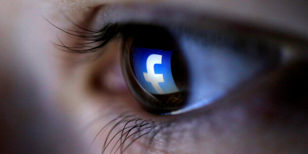 Eine Nahaufnahme eines Auges, in dem sich das Facebook-Symbol spiegelt Eine Nahaufnahme eines Auges, in dem sich das Facebook-Symbol spiegelt
