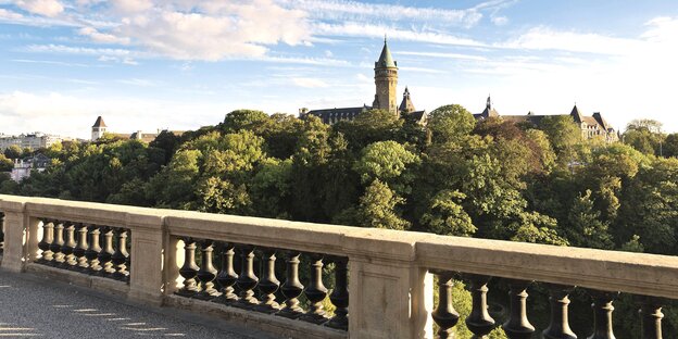 Blick auf eine Balustrade, dahinter erhebt sich ein bewaldeter Berg mit Turm Blick auf eine Balustrade, dahinter erhebt sich ein bewaldeter Berg mit Turm