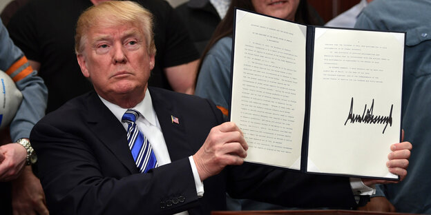 Donald Trump hält ein unterzeichnetes Dekret hoch Donald Trump hält ein unterzeichnetes Dekret hoch