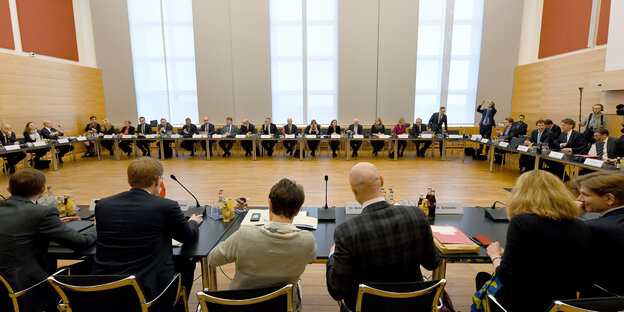 Viele Menschen in Anzügen sitzen in einem großen Kreis. Viele Menschen in Anzügen sitzen in einem großen Kreis.