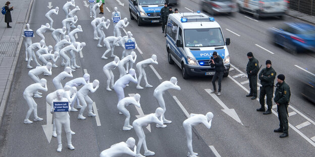 In weiß gekleidete Menschen stehen vor Polizisten In weiß gekleidete Menschen stehen vor Polizisten