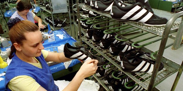 Eine Beschäftigte prüft Adidas Fußballschuhe Eine Beschäftigte prüft Adidas Fußballschuhe
