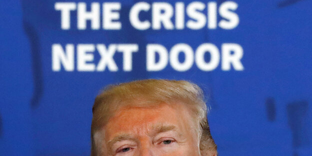 Donald Trump, über ihm steht an einer Wand The Crisis Next Door Donald Trump, über ihm steht an einer Wand The Crisis Next Door