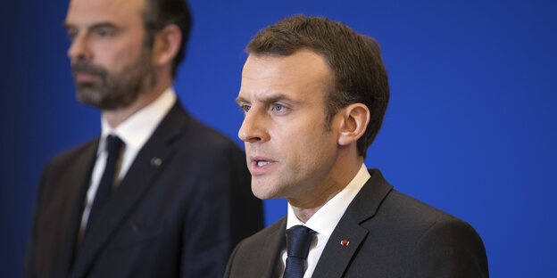 Emmanuel Macron steht vor einer blauen Wand Emmanuel Macron steht vor einer blauen Wand