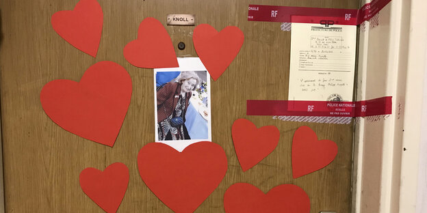 Rotes Tape, ein Polizeisiegel, Papierherzen und ein Bild von Mireille Knoll an einer Haustür Rotes Tape, ein Polizeisiegel, Papierherzen und ein Bild von Mireille Knoll an einer Haustür