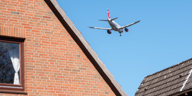 Ein Flugzeug fliegt über einem Einfamilienhaus Ein Flugzeug fliegt über einem Einfamilienhaus