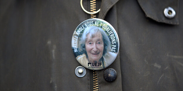 Ein Button mit einer Potrait der ermordeten Mireille Knoll hängt an einer Jacke Ein Button mit einer Potrait der ermordeten Mireille Knoll hängt an einer Jacke