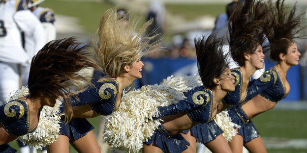 Cheerleader tanzen mit Pompons in knappen Outfits Cheerleader tanzen mit Pompons in knappen Outfits