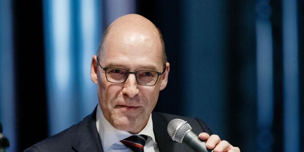 Ein Mann mit Gllatze, Brille und Mikrophon in der Hand Ein Mann mit Gllatze, Brille und Mikrophon in der Hand