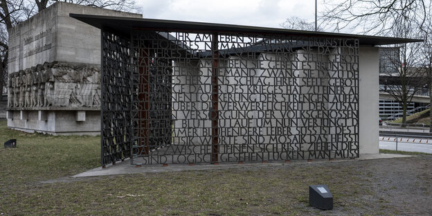 Ein Denkmal mit marschierenden Soldaten und eines mit einem Text aus gegossenen Buchstaben. Ein Denkmal mit marschierenden Soldaten und eines mit einem Text aus gegossenen Buchstaben.
