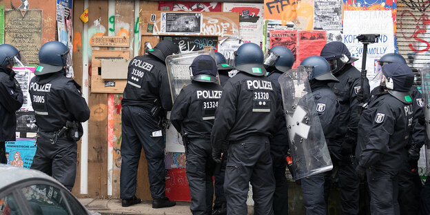 Mehrere Polizisten in Riotgear vor einem Hauseingang Mehrere Polizisten in Riotgear vor einem Hauseingang