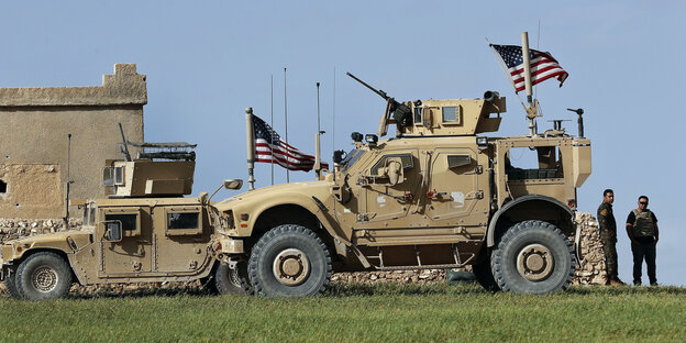 Soldaten stehen neben Militärfahrzeugen über denen US-amerikanische Fahnen wehen Soldaten stehen neben Militärfahrzeugen über denen US-amerikanische Fahnen wehen