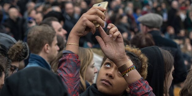 Eine junge Frau macht ein Selfie von sich und eine Demonstration im Hintergrund Eine junge Frau macht ein Selfie von sich und eine Demonstration im Hintergrund