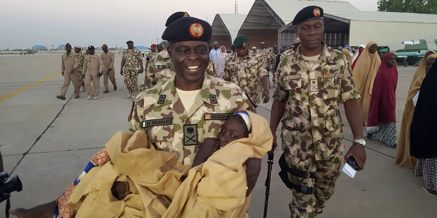 Ein General trägt ein zurückgebrachtes Mädchen, das von der Boko-Haram-Miliz entführt wurde Ein General trägt ein zurückgebrachtes Mädchen, das von der Boko-Haram-Miliz entführt wurde