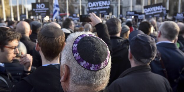 Viele Menschen demonstrieren mit Schildern auf einem Platz, einige Demonstranten tragen Kippa