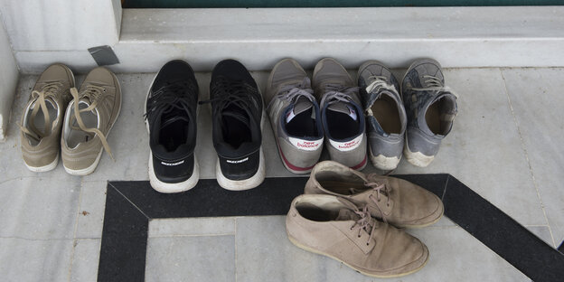 Mehrere Paar Schuhe vor einer Tür Mehrere Paar Schuhe vor einer Tür