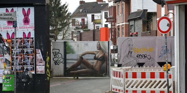 Eine Mauer und zwei Wände mit Bildern von Frauen in Unterwäsche versperren die Sicht in eine Straße. Eine Mauer und zwei Wände mit Bildern von Frauen in Unterwäsche versperren die Sicht in eine Straße.
