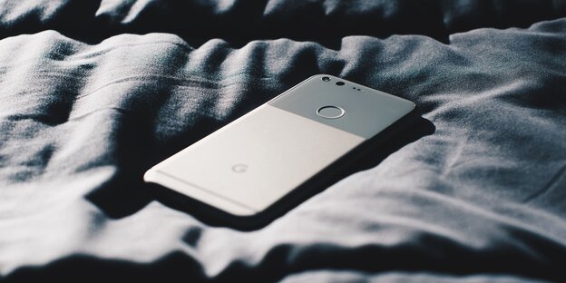 Ein Handy liegt auf einem Bett Ein Handy liegt auf einem Bett