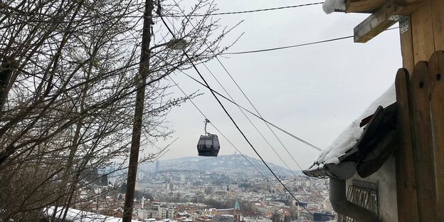 Die Gondel einer Bergstation hängt über der Stadt Die Gondel einer Bergstation hängt über der Stadt