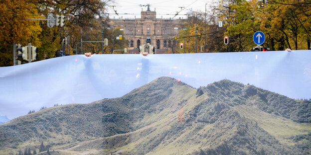Leute halten ein Transparent hoch, auf dem Berge zu sehen sind Leute halten ein Transparent hoch, auf dem Berge zu sehen sind