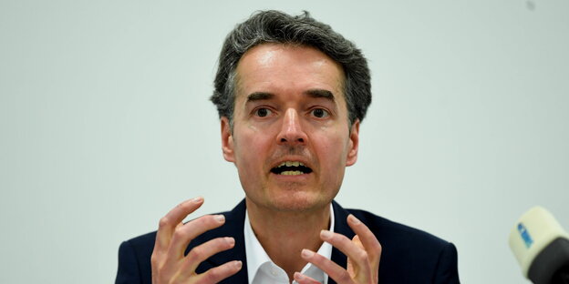 ein Mann spricht in Mikrofone und ringt die Hände ein Mann spricht in Mikrofone und ringt die Hände