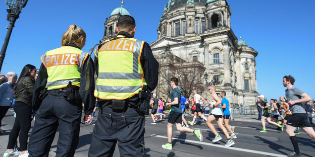 Zwei Polizisten stehen an der Halbmarathonstrecke in Berlin vor dem Dom. Zwei Polizisten stehen an der Halbmarathonstrecke in Berlin vor dem Dom.