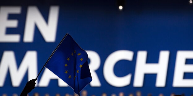 Jemand hält eine Europafahne vor einem En-Marche-Banner Jemand hält eine Europafahne vor einem En-Marche-Banner