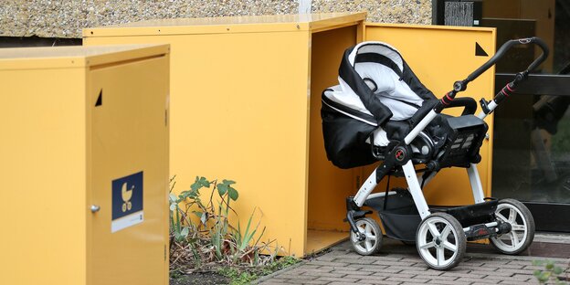 Ein Kinderwagen steht vor einem Kasten Ein Kinderwagen steht vor einem Kasten