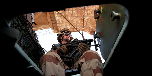Ein Soldat sitzt auf einem Militärfahrzeug und hält ein Gewehr in der Hand Ein Soldat sitzt auf einem Militärfahrzeug und hält ein Gewehr in der Hand