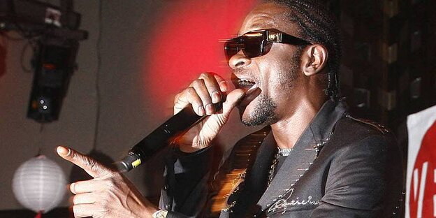 Zwei schwarze Musiker auf einer Bühne, einer trägt eine dunkle Sonnenbrille Zwei schwarze Musiker auf einer Bühne, einer trägt eine dunkle Sonnenbrille
