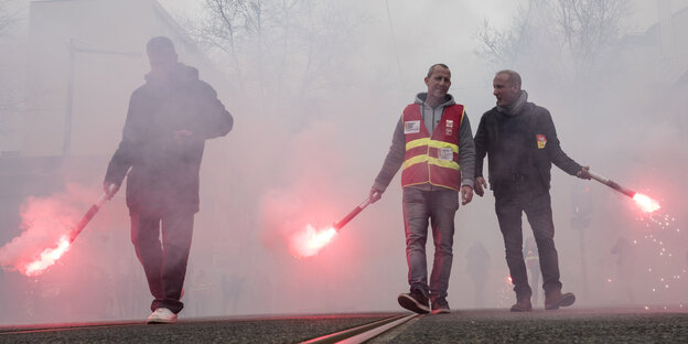 Drei Männer halten im Nebel bengalisches Feuer in ihren Hänen Drei Männer halten im Nebel bengalisches Feuer in ihren Hänen
