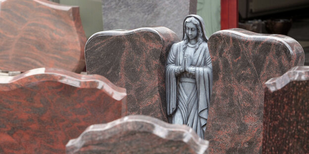 Ein Grabstein mit einer Figur, die die Hände faltete. Ein Grabstein mit einer Figur, die die Hände faltete.