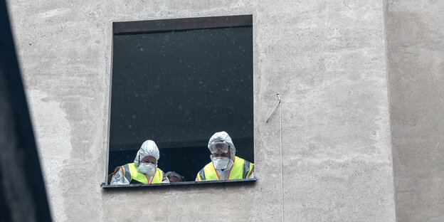 Polizisten mit Schutzmasken schauen aus dem Fenster