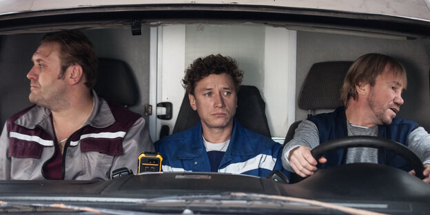Drei Männer sitzen nebeneinander in einem Auto Drei Männer sitzen nebeneinander in einem Auto