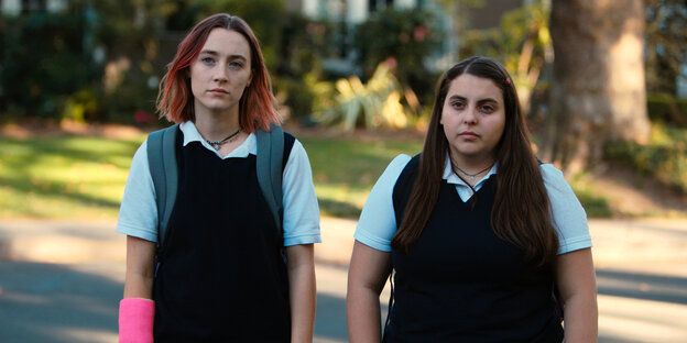 Lady Bird und ihre Freundin stehen nebeneinander auf der Straße und schauen gelangweilt Lady Bird und ihre Freundin stehen nebeneinander auf der Straße und schauen gelangweilt